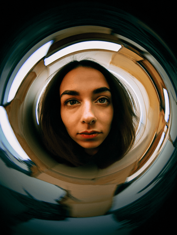 A woman standing and looking directly at the camera under the special perspective of a fisheye lens